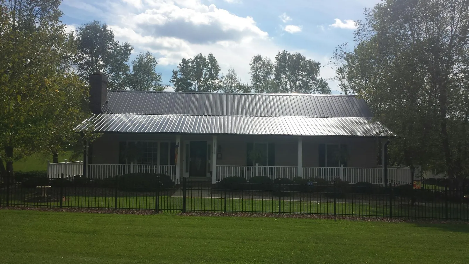 Gray metal roof on a brick ranch with a full width front porch — Gutter Guard Installation work by our crew in Dexter City