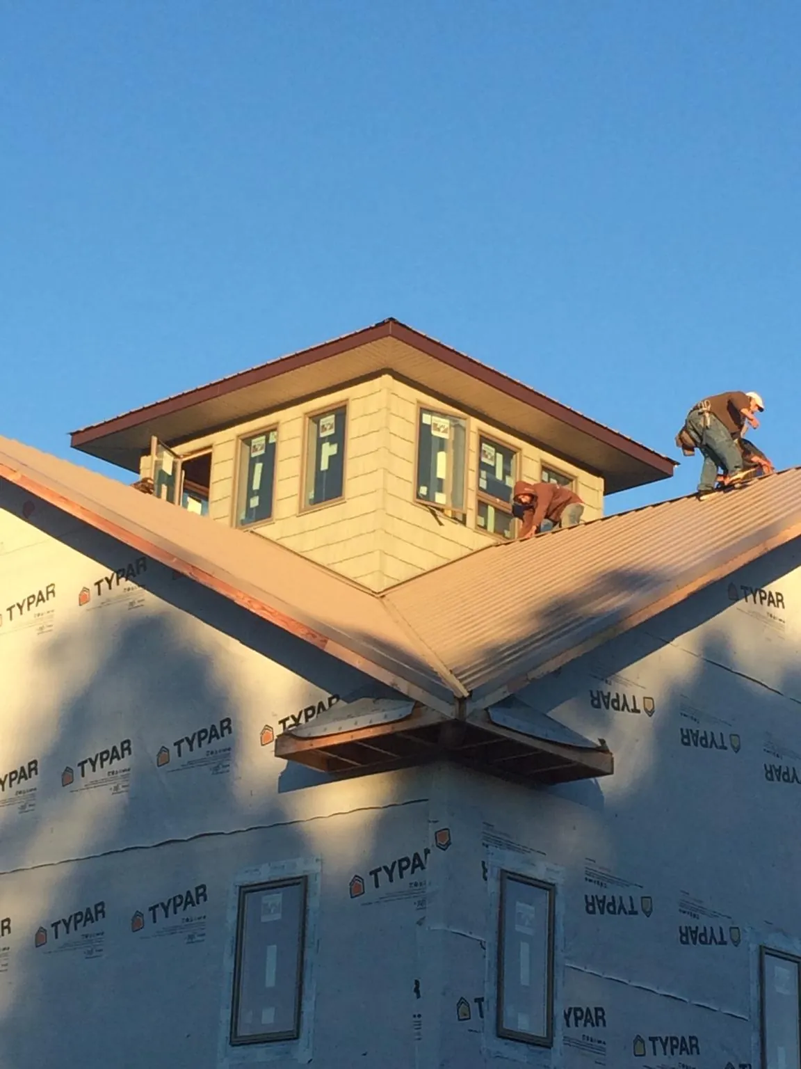 Roofers working around a rooftop cupola on a new metal roof at sunset — Roof Waterproofing in Dexter City by Roofing Brothers